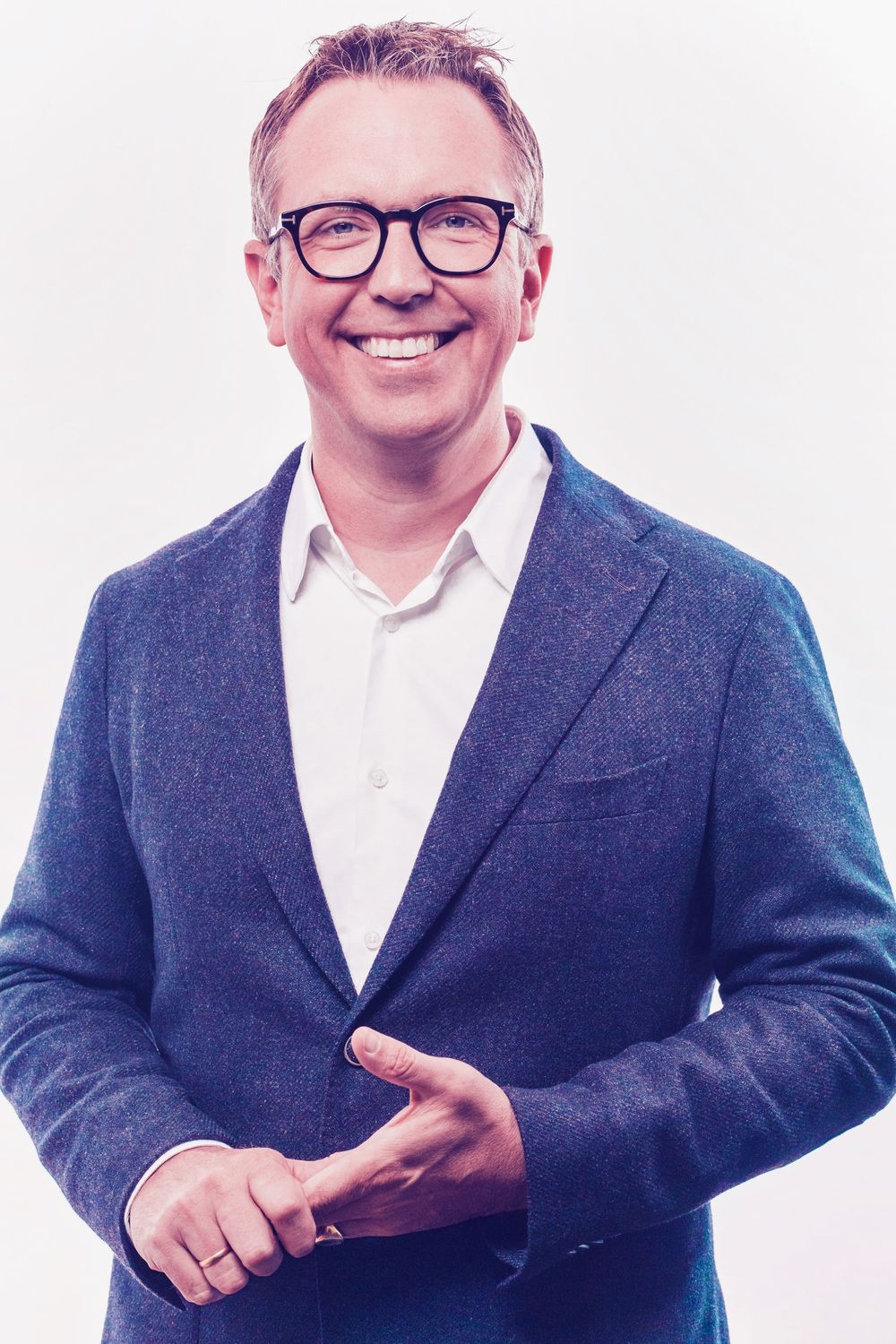 Professional wearing navy blazer and glasses smiling in multiple poses against white background.