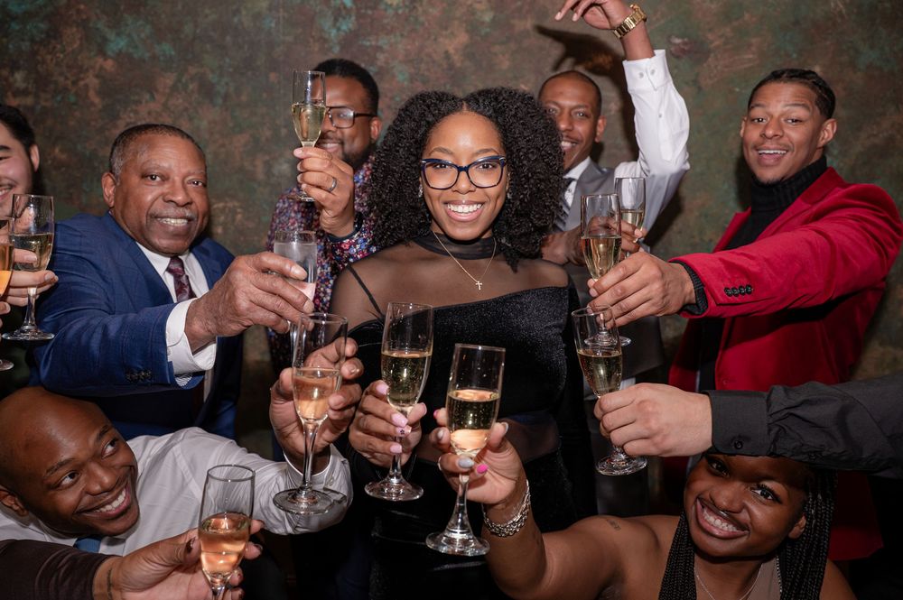 A celebratory group raises champagne glasses in a toast during a festive gathering.