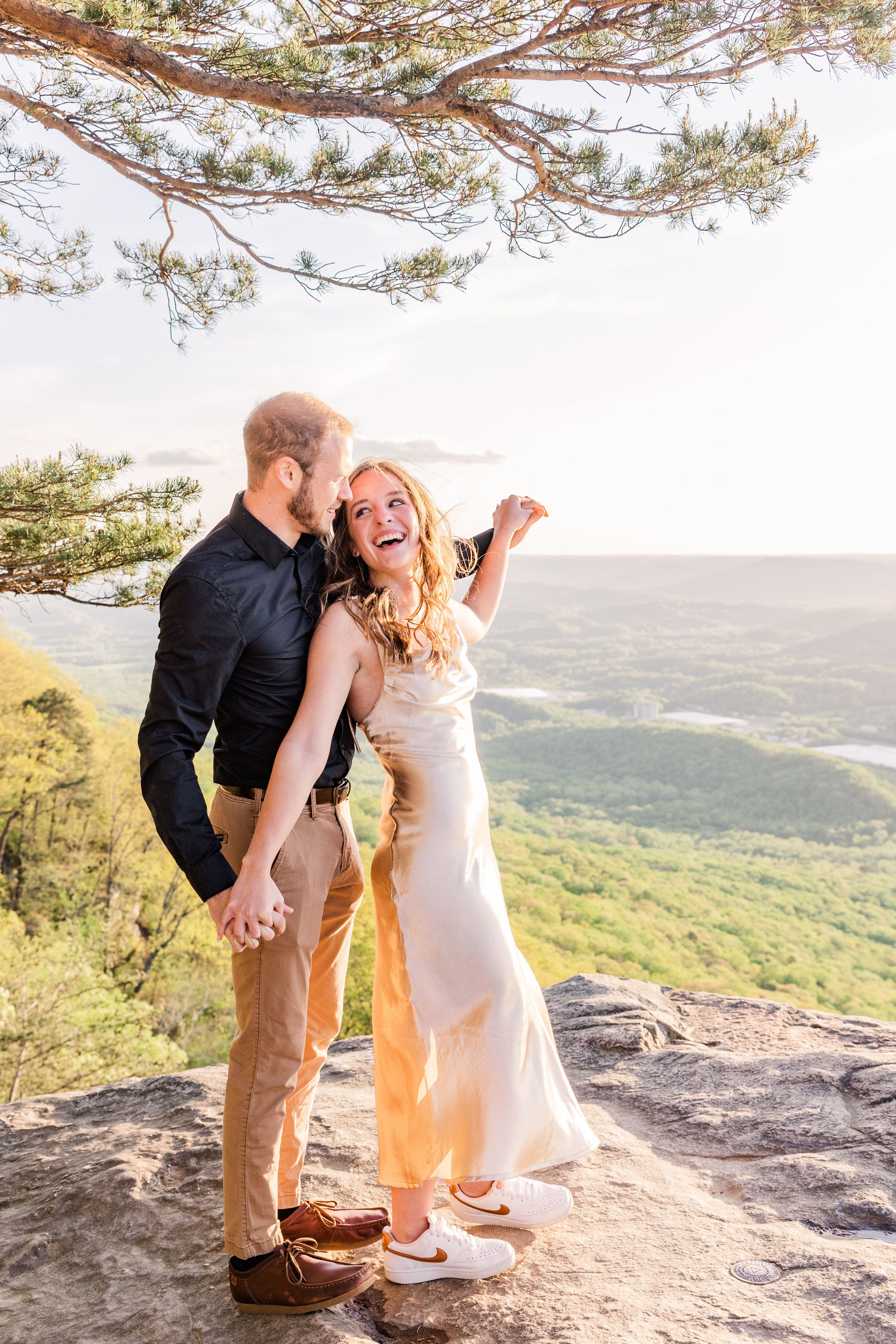 Happy couple sharing joyful moment on scenic mountain cliff.