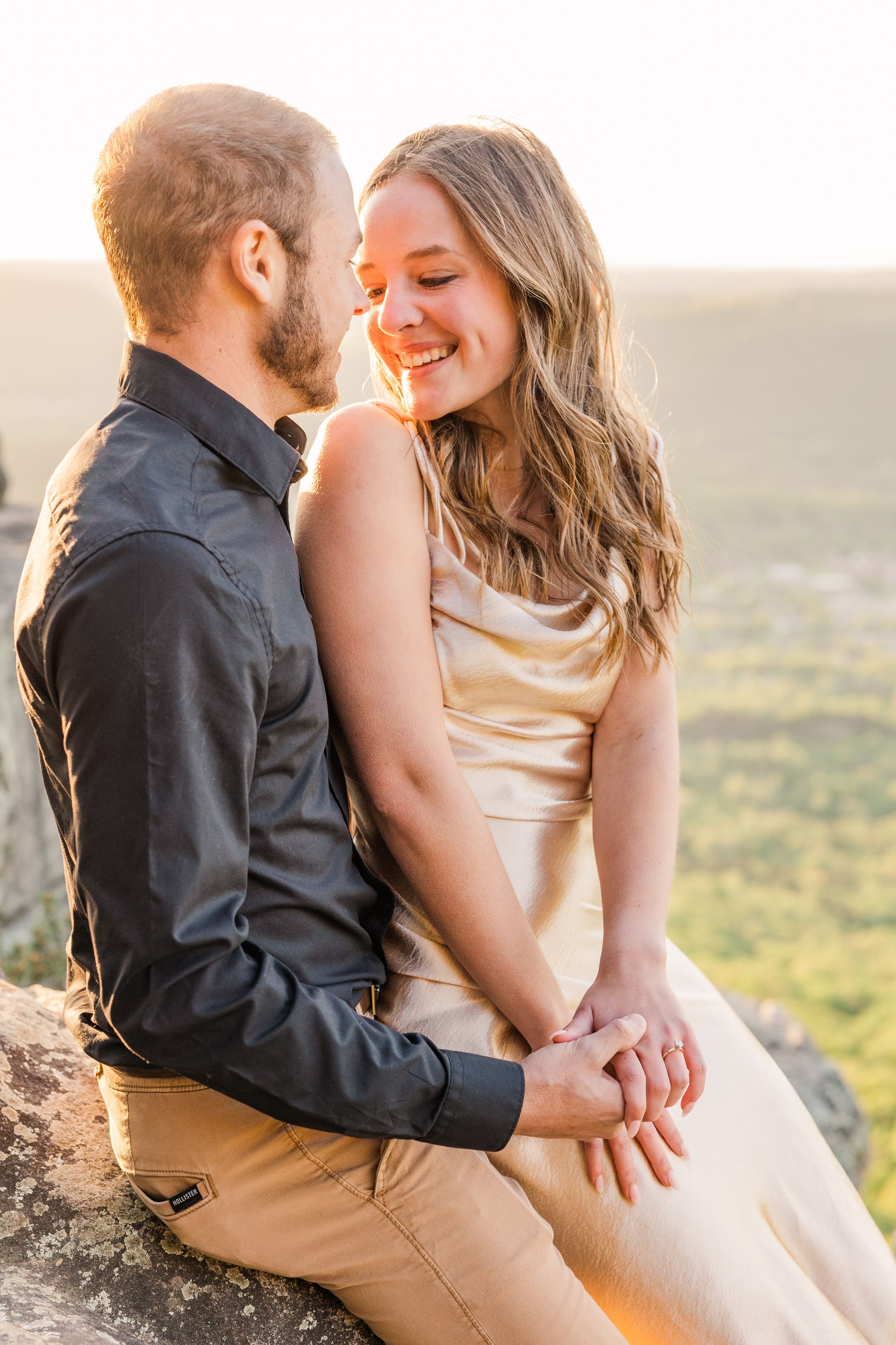Intimate moment between couple on rocky mountain overlook.