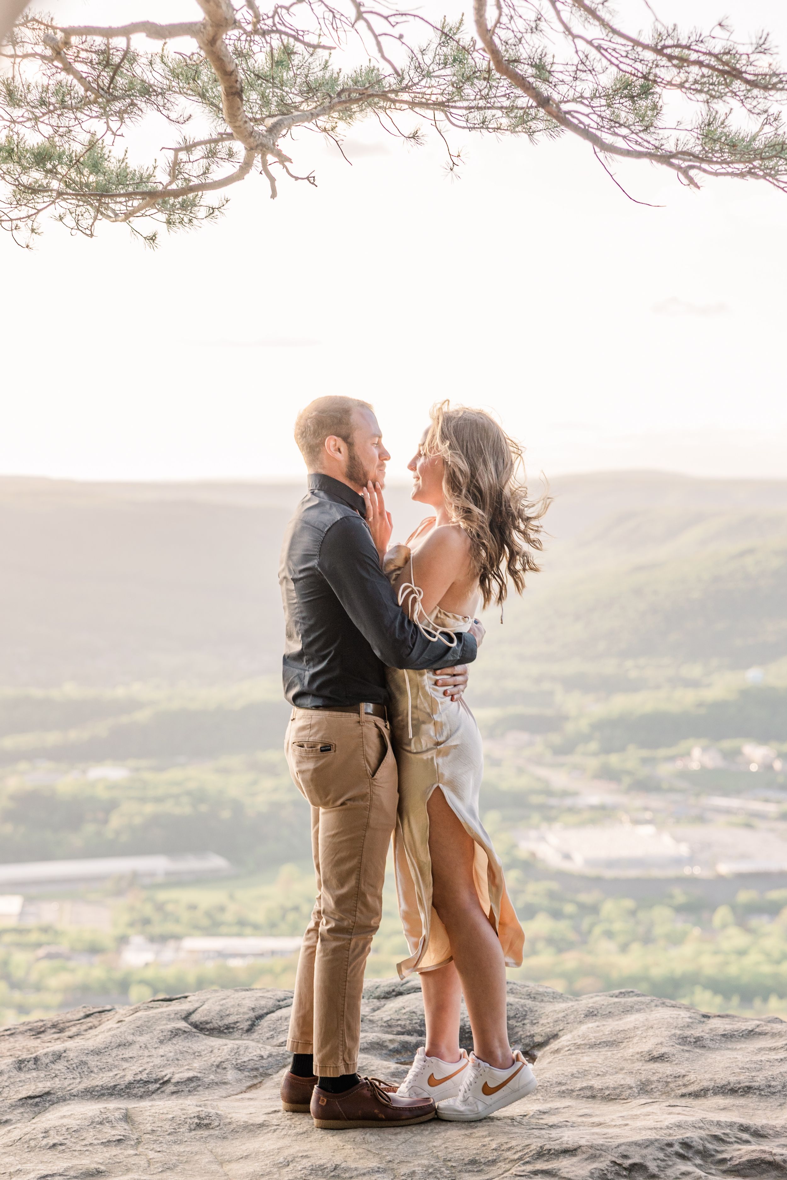 Couple embracing on rocky mountain overlook with valley views.