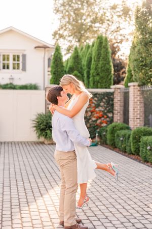 A couple shares a joyful moment dancing together on a brick patio during sunset.