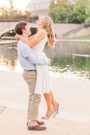 A couple laughs and embraces by a reflecting pool during golden hour.