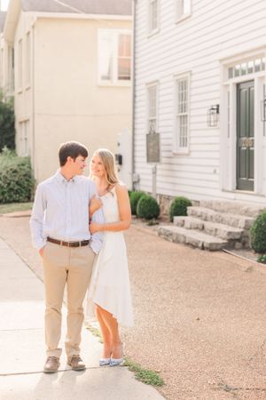 Romantic couple in summer attire sharing intimate moment outside classic white building.