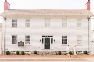 White colonial style building with symmetrical windows and classic green door entrance.
