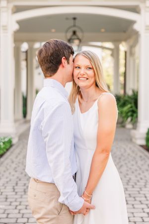 Romantic moment between couple under white archway with pendant lighting.