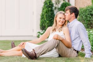 Couple relaxing on grass in casual summer attire during outdoor photoshoot.
