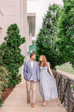Couple walking along a tree-lined pathway wearing coordinated blue and khaki outfits.