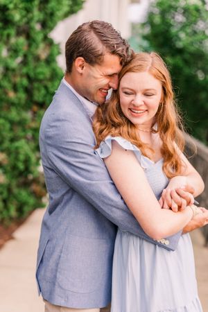 A joyful embrace captured in a sunlit outdoor setting with lush greenery.