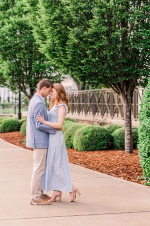 A romantic moment shared between a couple on a landscaped pathway with mulch and trees.