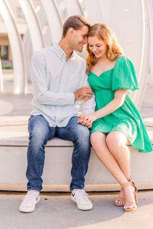 A couple shares an intimate moment while sitting on concrete steps in casual attire.