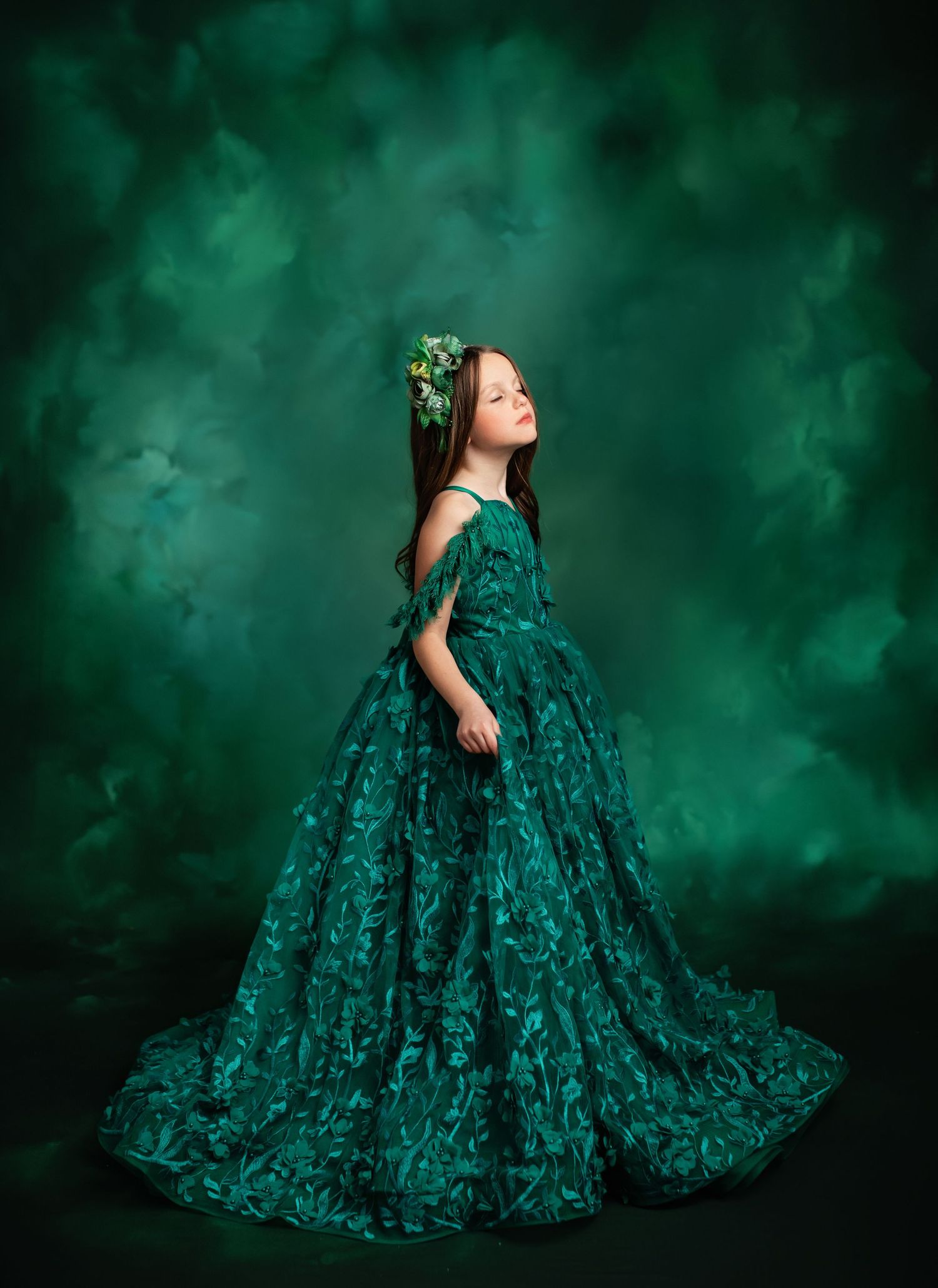 Elegant emerald green ball gown with lace details set against a mystical dark green background.