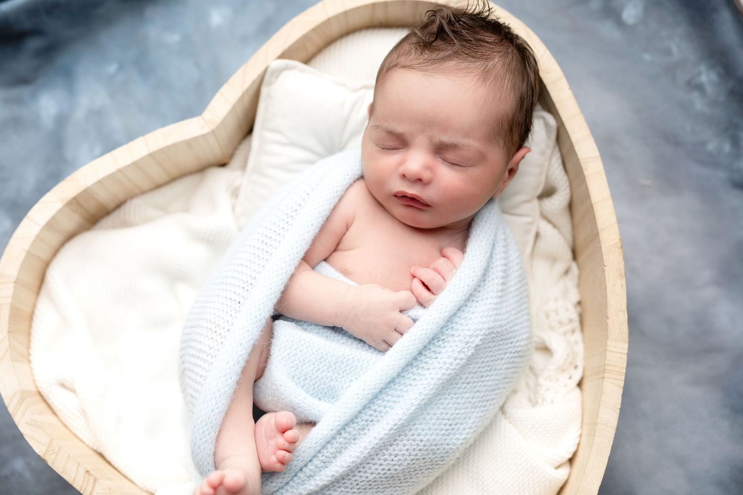 Sleeping newborn baby wrapped in light blue blankets against a dreamy winter backdrop.