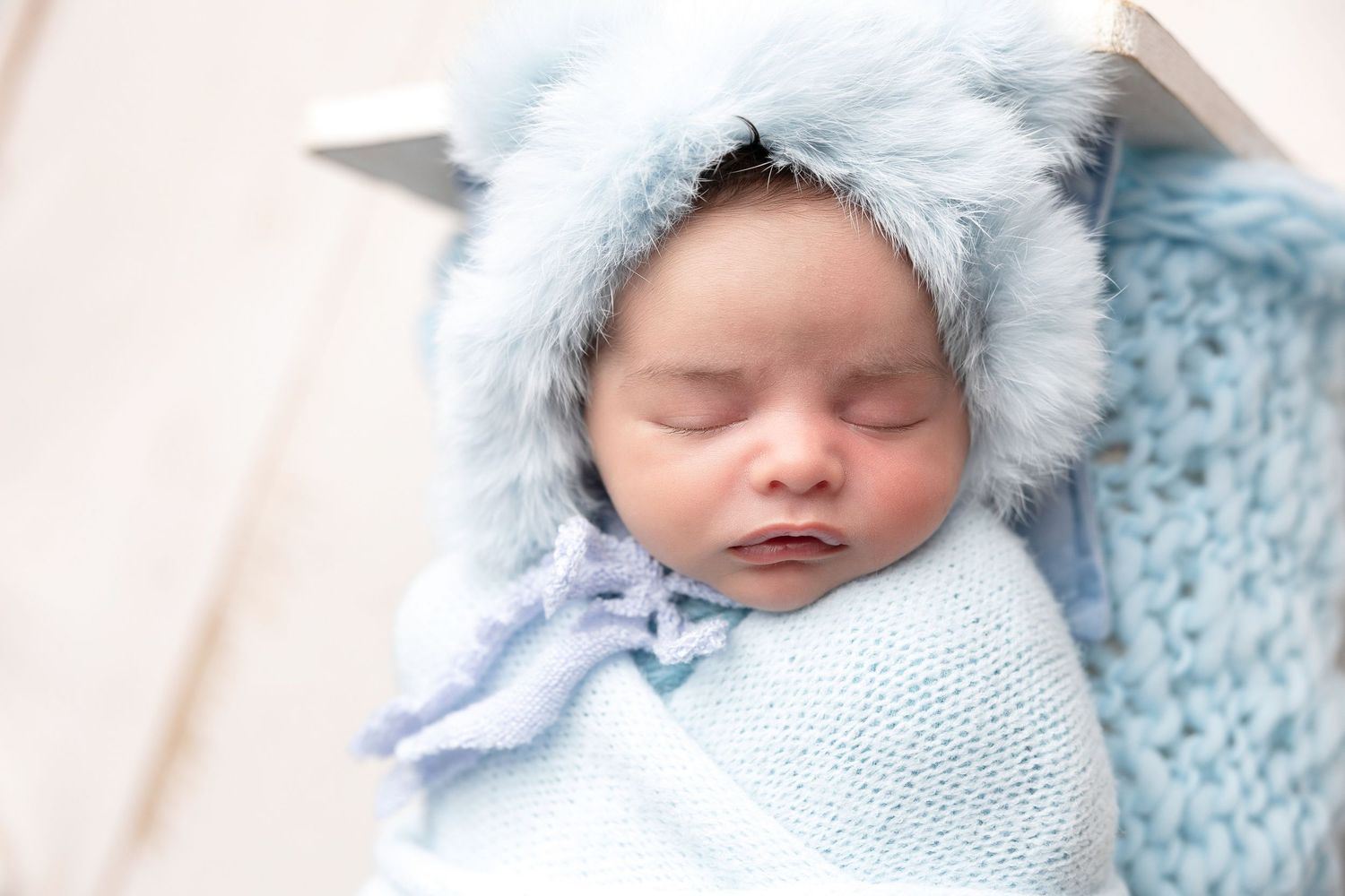 Peaceful sleeping newborn wearing a soft blue bonnet in a series of gentle portraits.