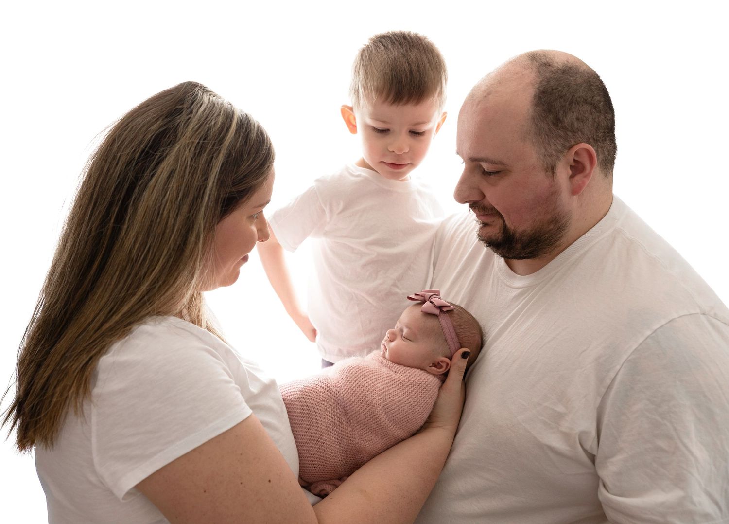 Intimate family portrait in white outfits with newborn.
