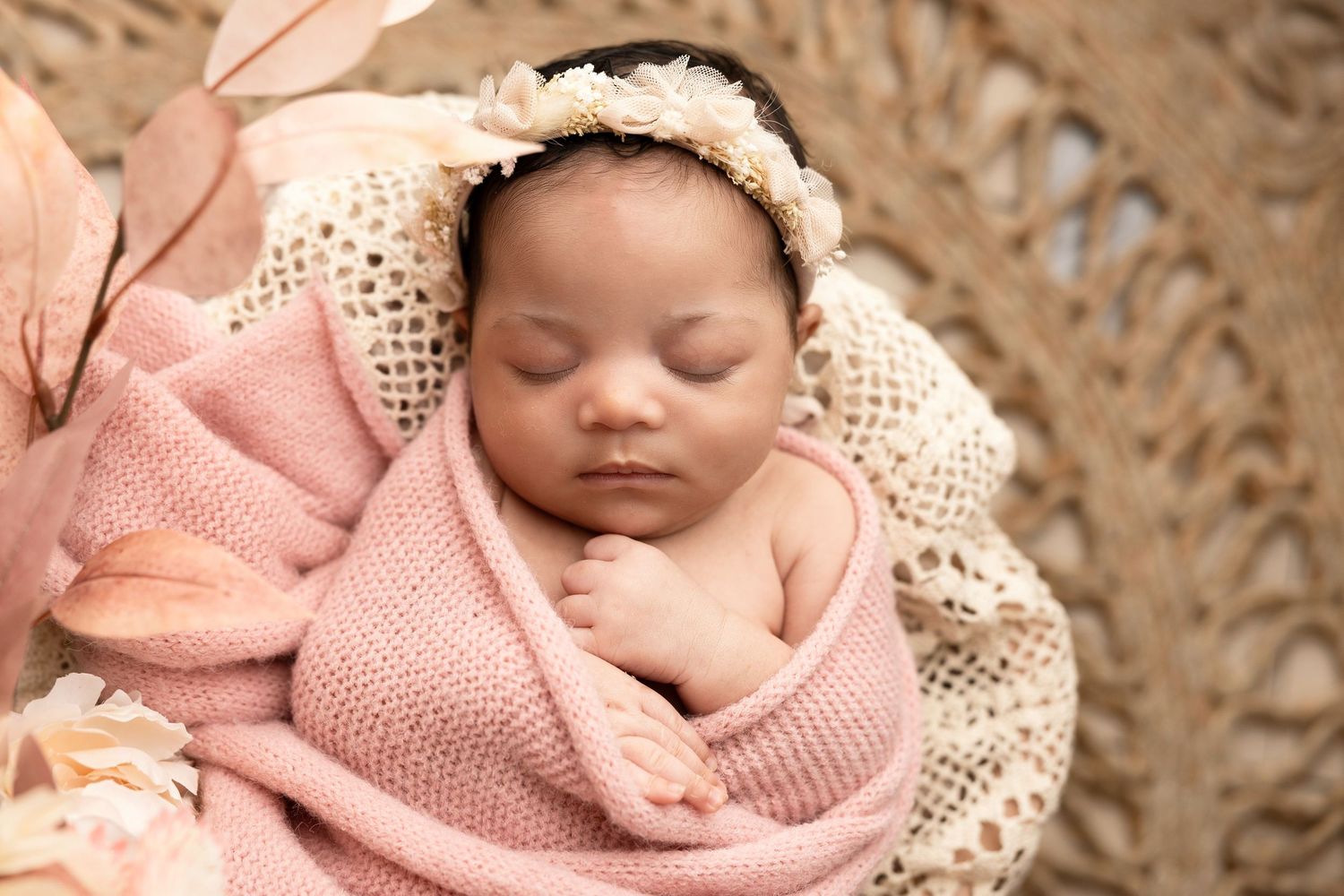 Newborn photography with soft pink wrapping and delicate lace details.
