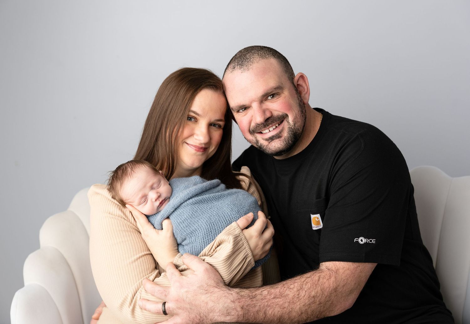 Family portrait session with newborn baby in studio against grey background.