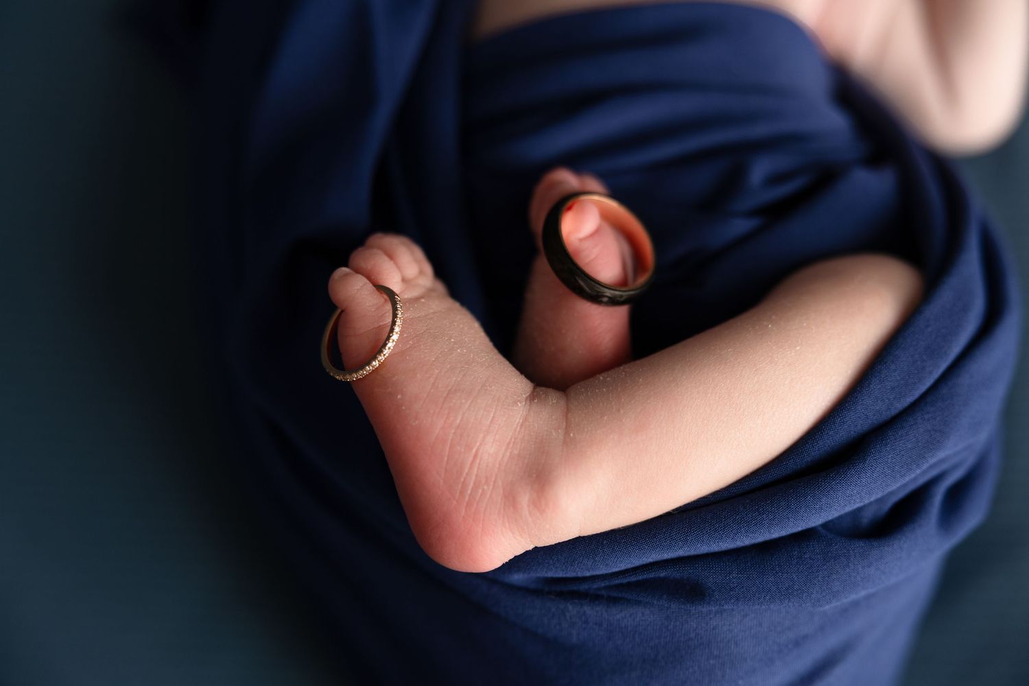 Close-up details of newborn wrapped in navy blue fabric.