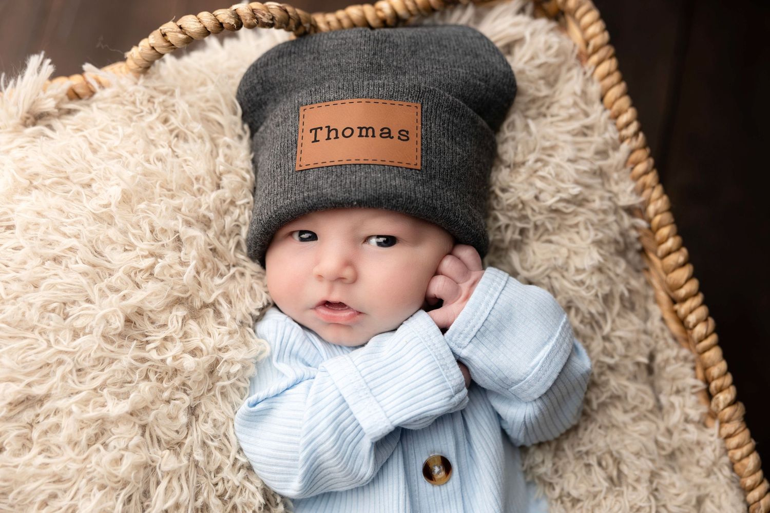 Baby wearing knit hat and sweater in cozy setting.