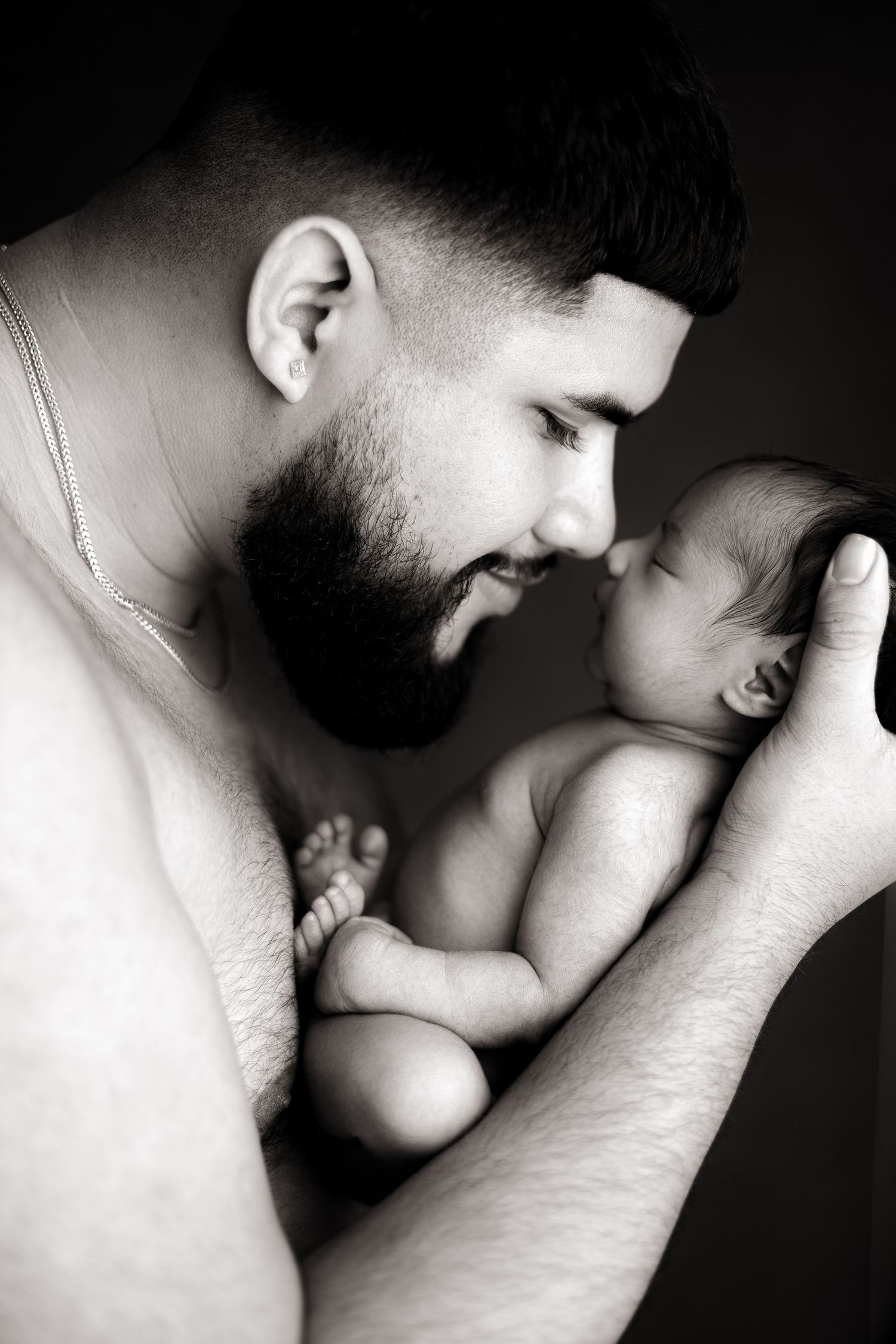 Intimate black and white portrait of tender moment between parent and newborn.