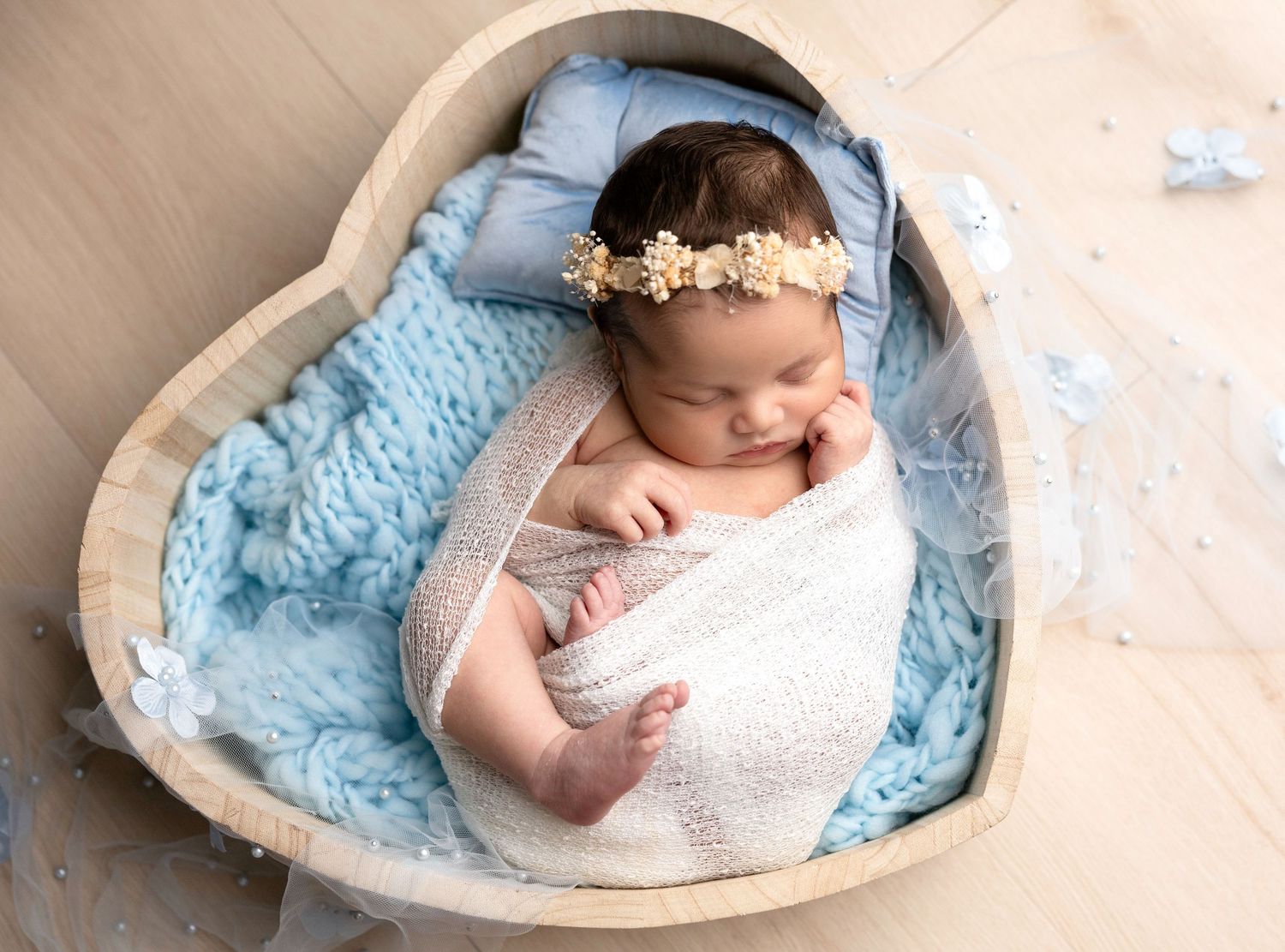 Newborn photography series with baby nestled in heart-shaped basket with blue accents.