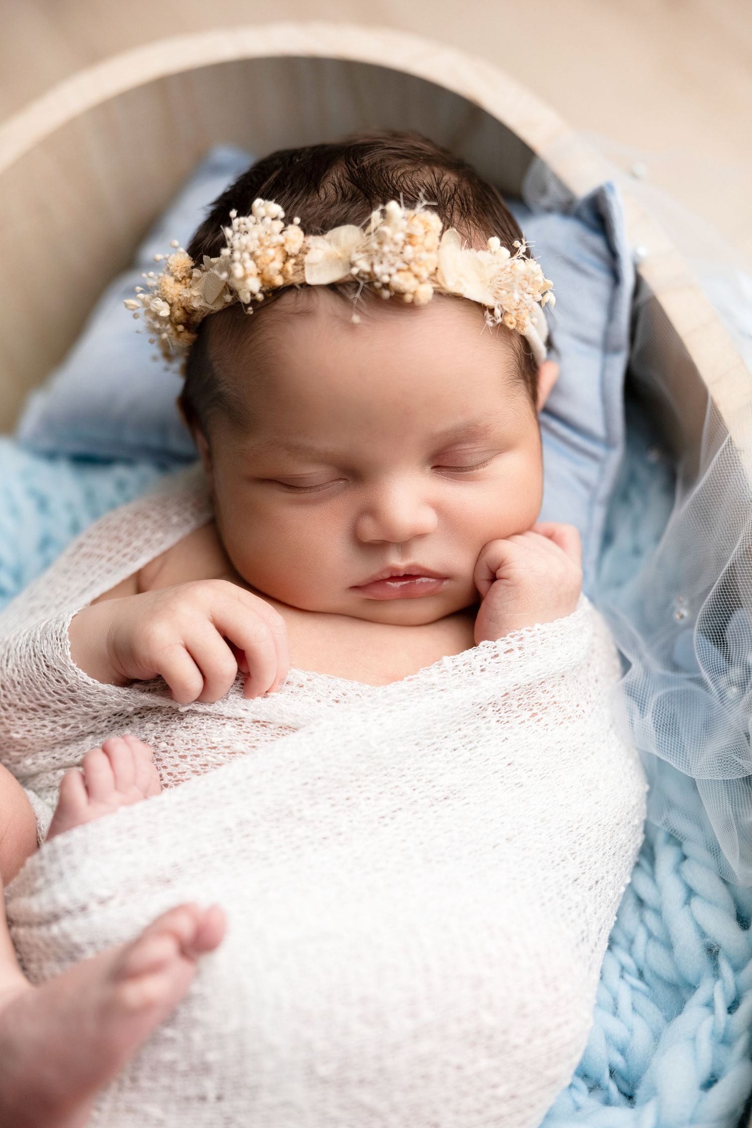 Close-up newborn portraits featuring delicate lace wrap and floral headpiece.