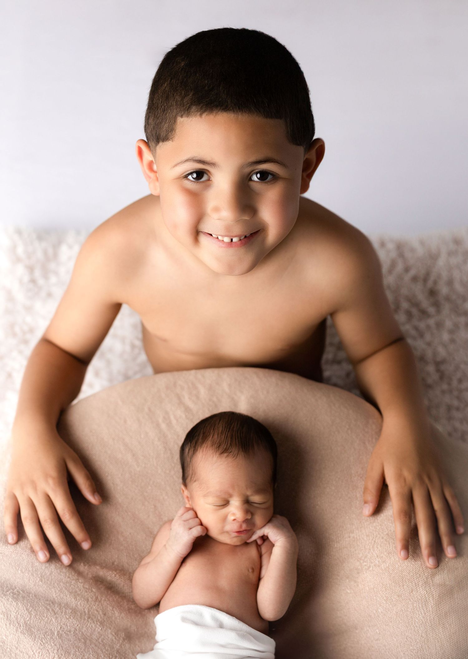 Heartwarming sibling portrait on neutral backdrop.