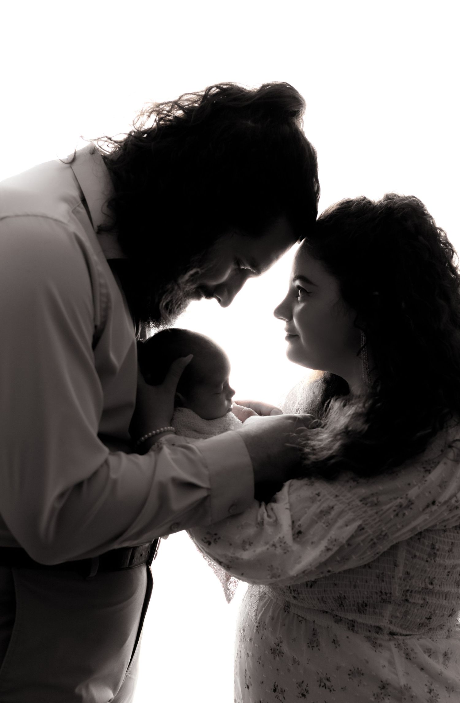 Silhouette portrait of family with newborn in tender moment.