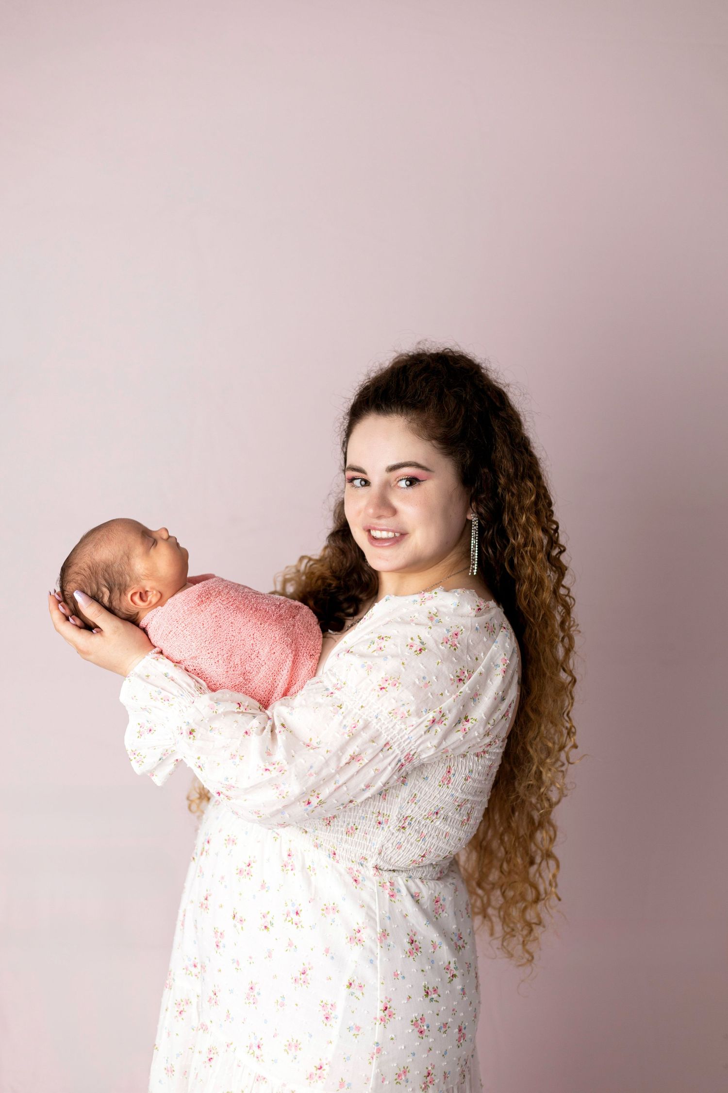 Series showing woman in floral dress holding newborn baby in different poses.
