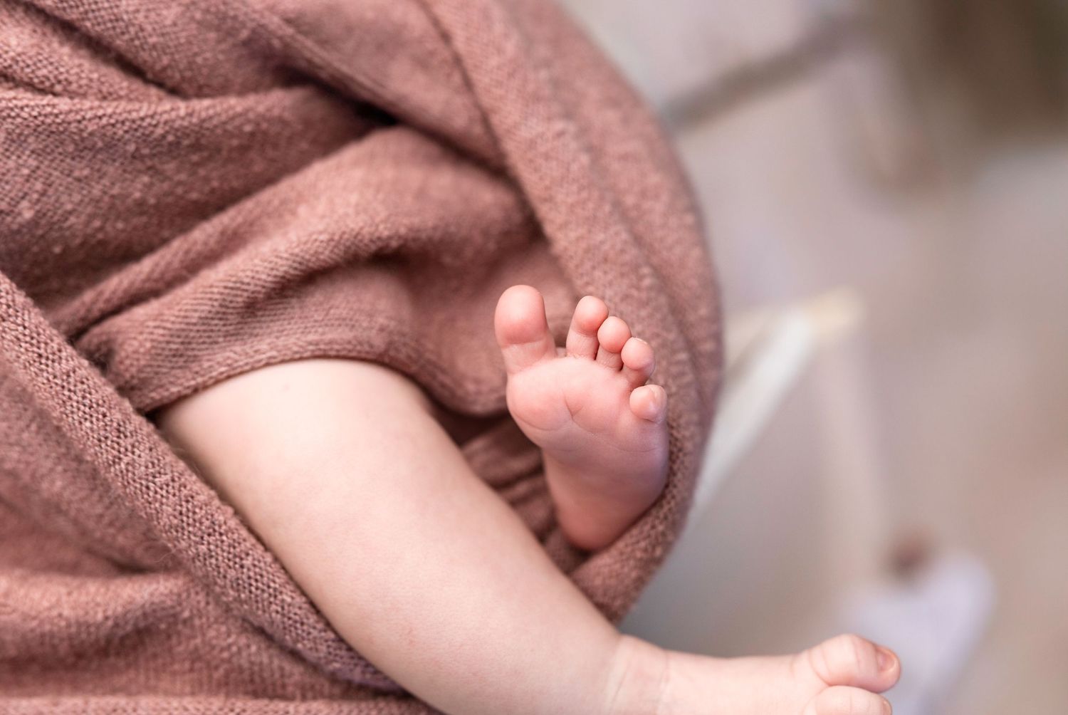 Series of artistic close-up shots showing baby's tiny features and pink wrapping.
