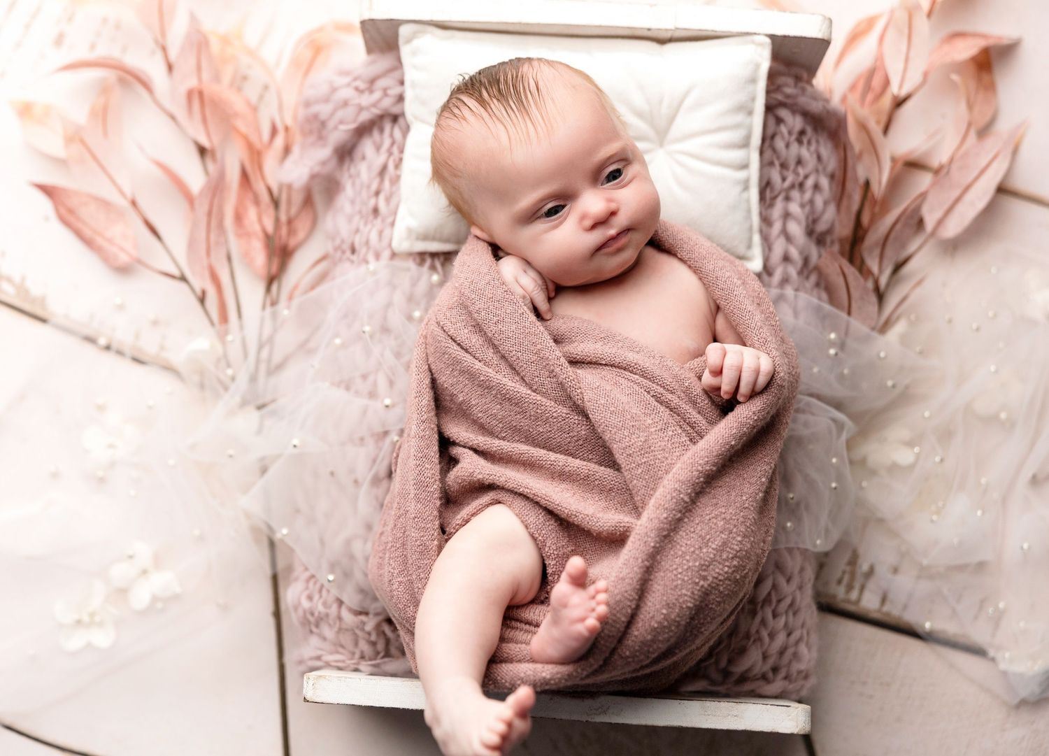Artistic newborn photography series with soft pink tones and white textures.
