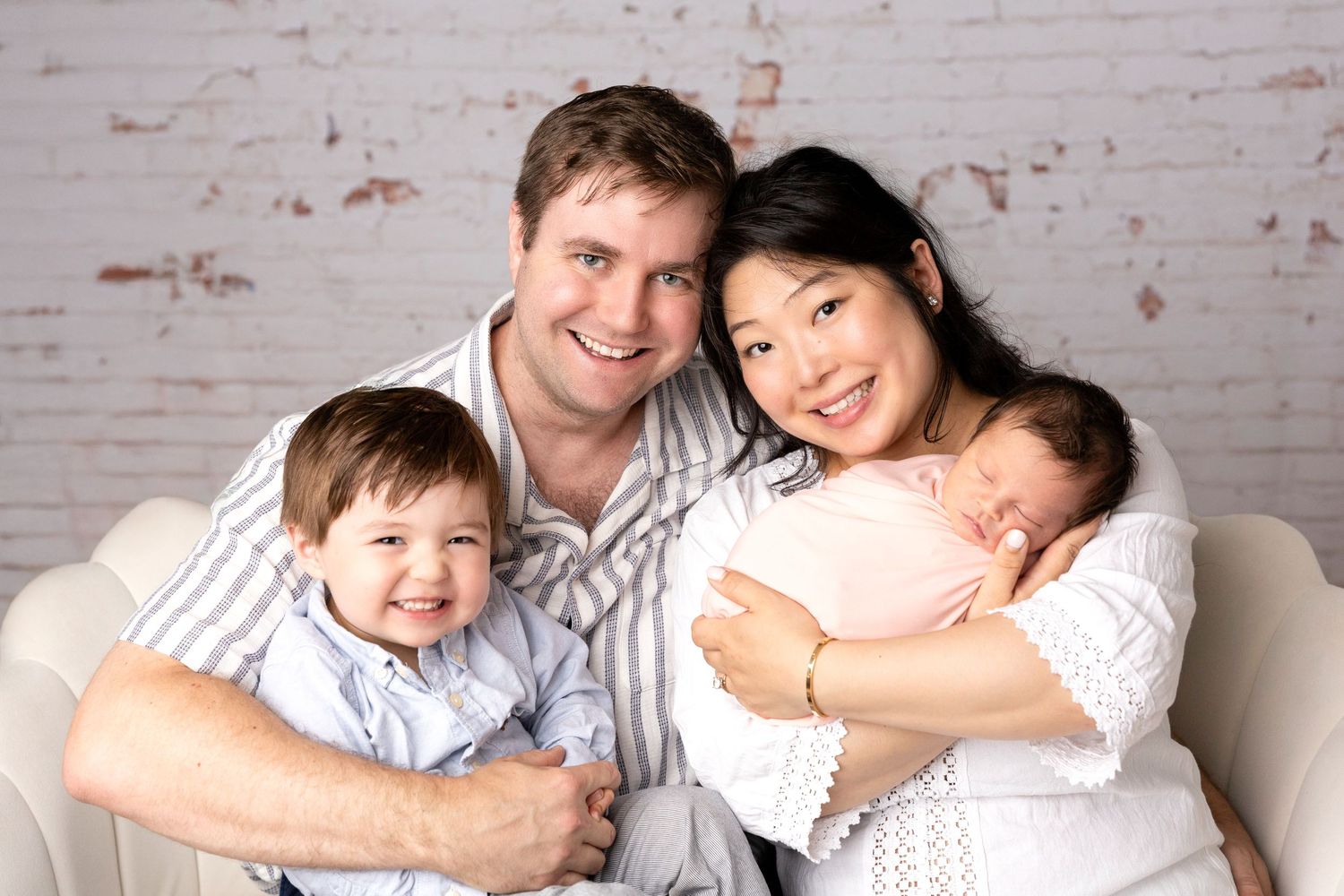 Family portrait series against white brick wall showing tender moments together.