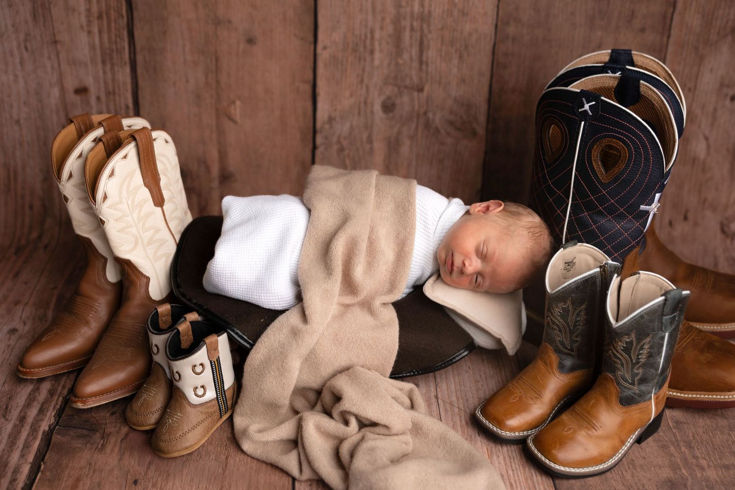 Collection of cowboy boots lined up against rustic wooden background.