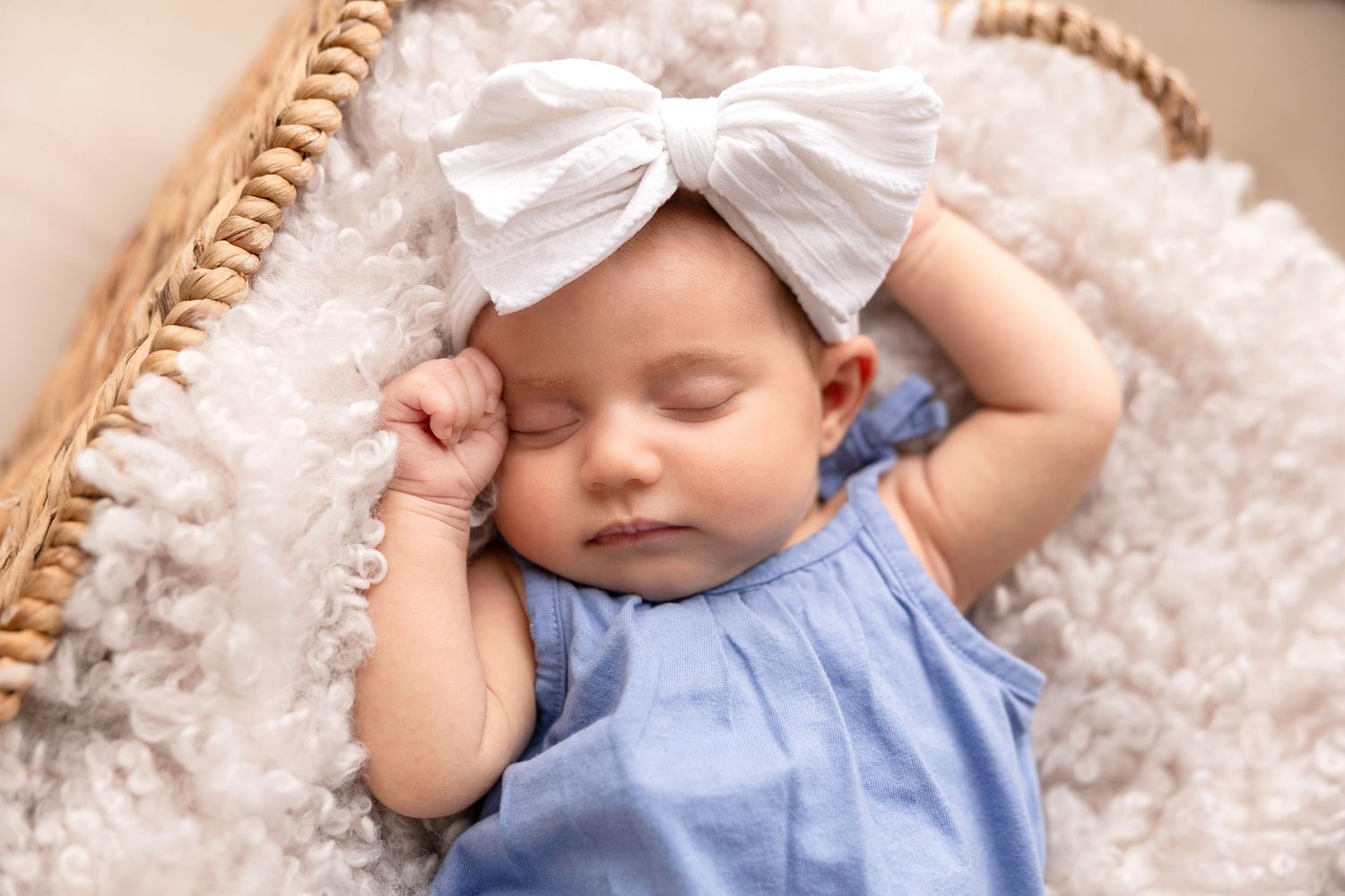 Newborn photography session with blue floral decorations and soft white textiles.