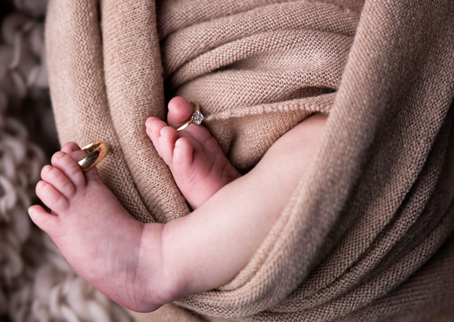 Close-up sequence of tiny baby feet wrapped in soft brown blanket.