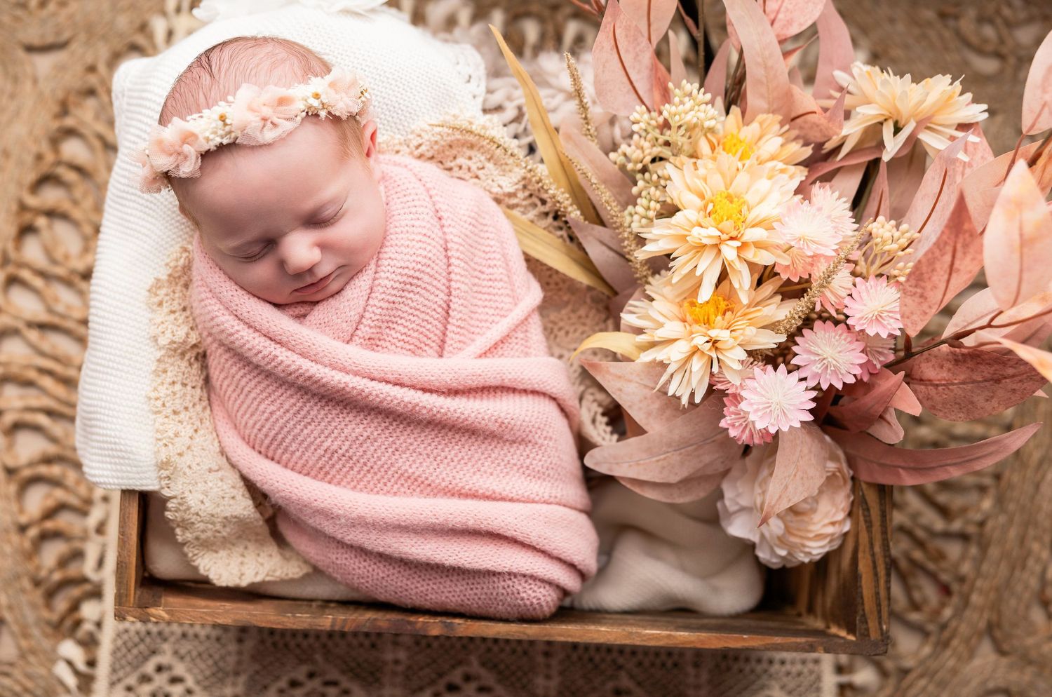 Peaceful newborn photography with soft pink flowers and delicate wrapping.