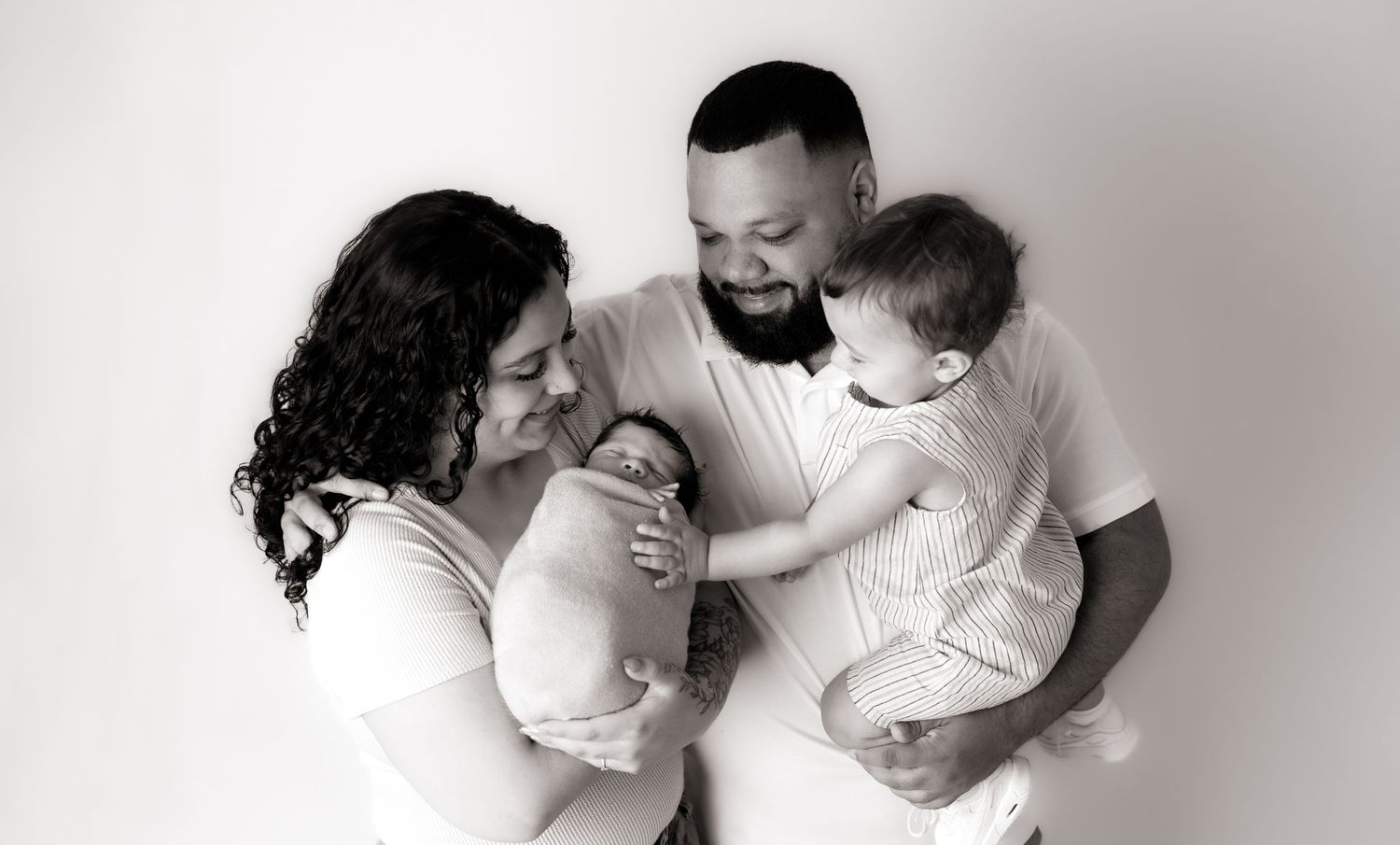 Black and white family photo with parents and baby lying down together.