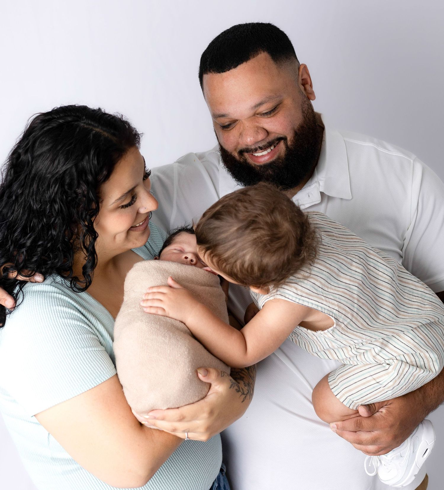Family members cuddling together on white background in casual attire.