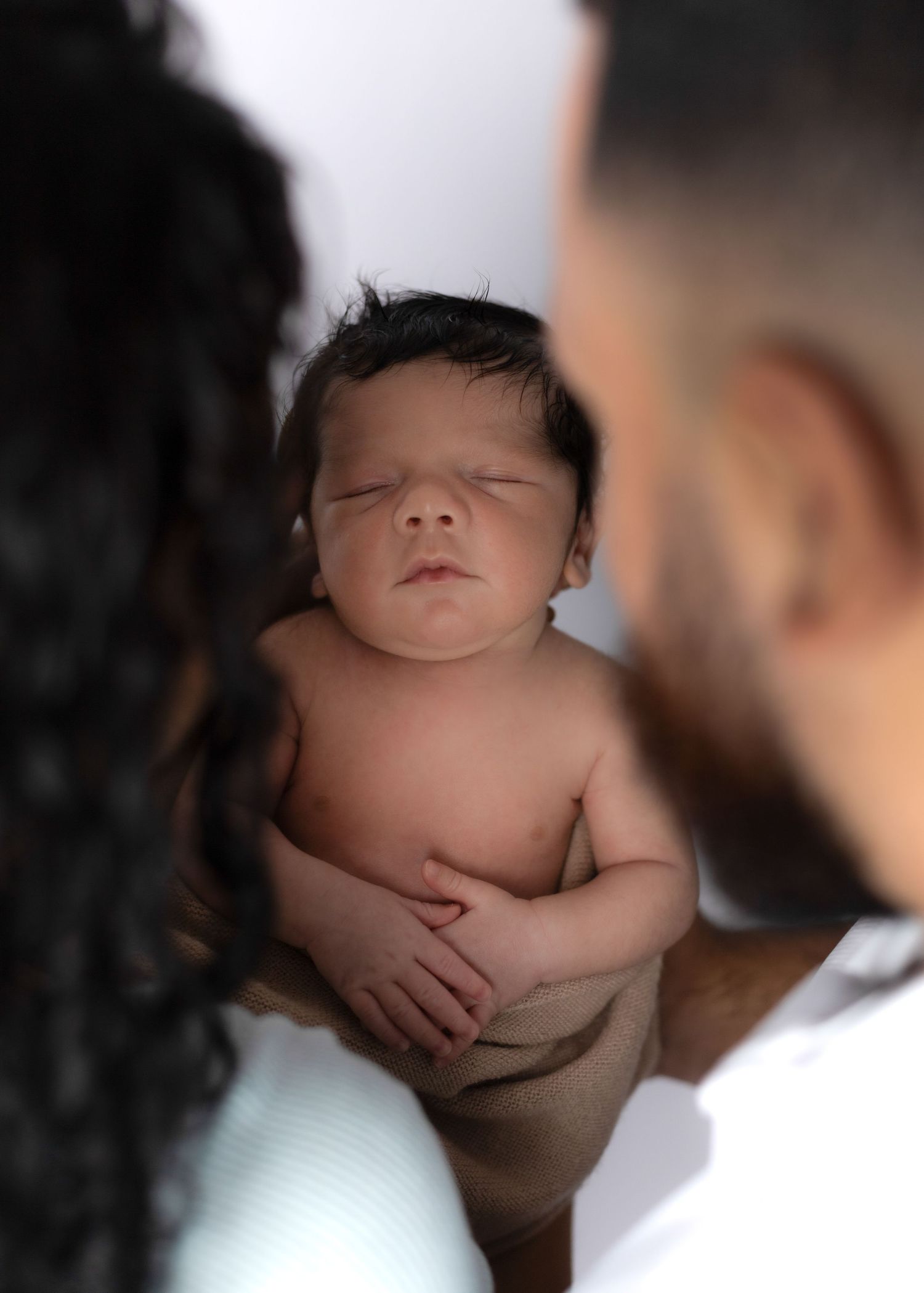 Intimate family portrait with gentle embraces in soft lighting.