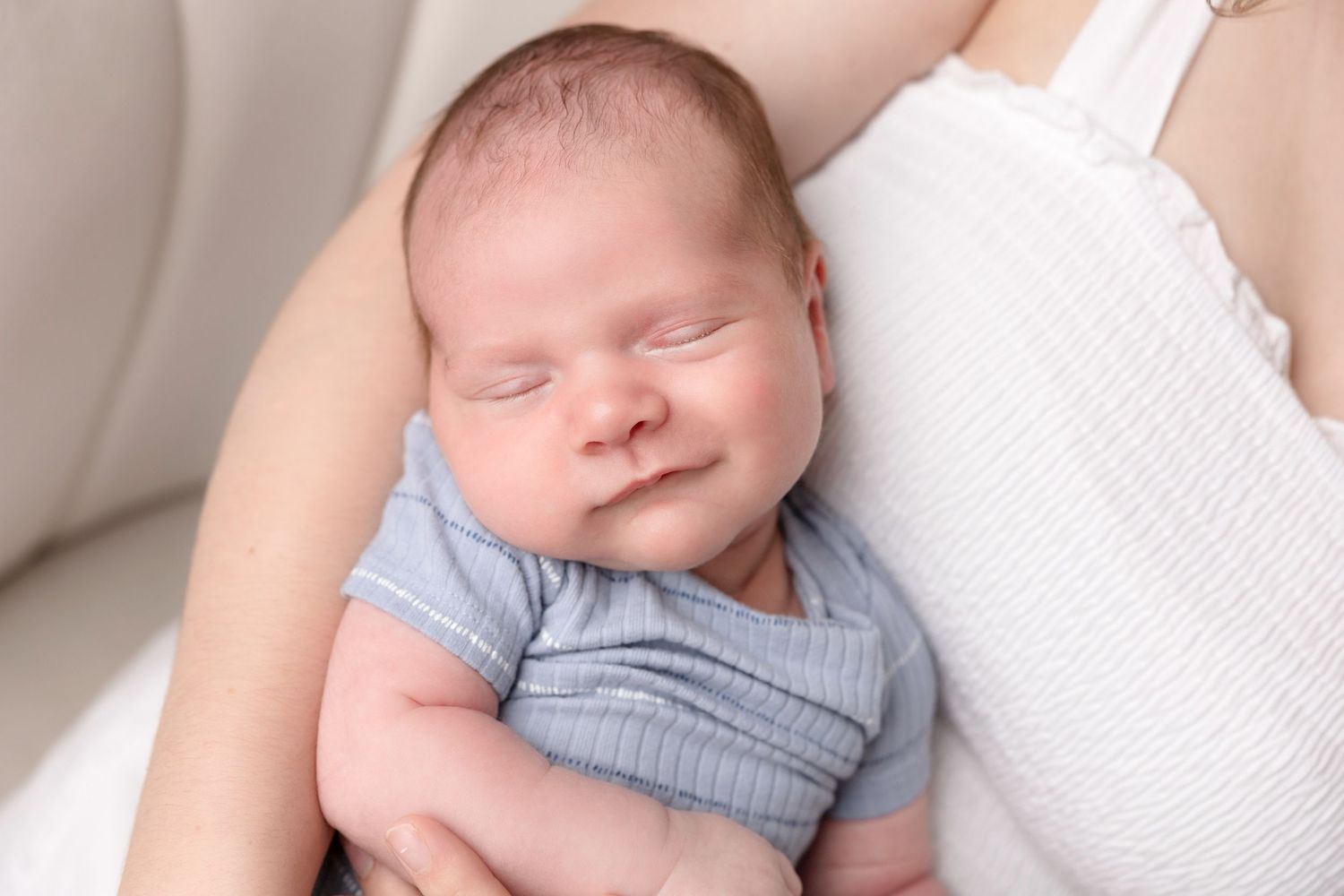 Sweet newborn photo series with soft white textiles and natural lighting.