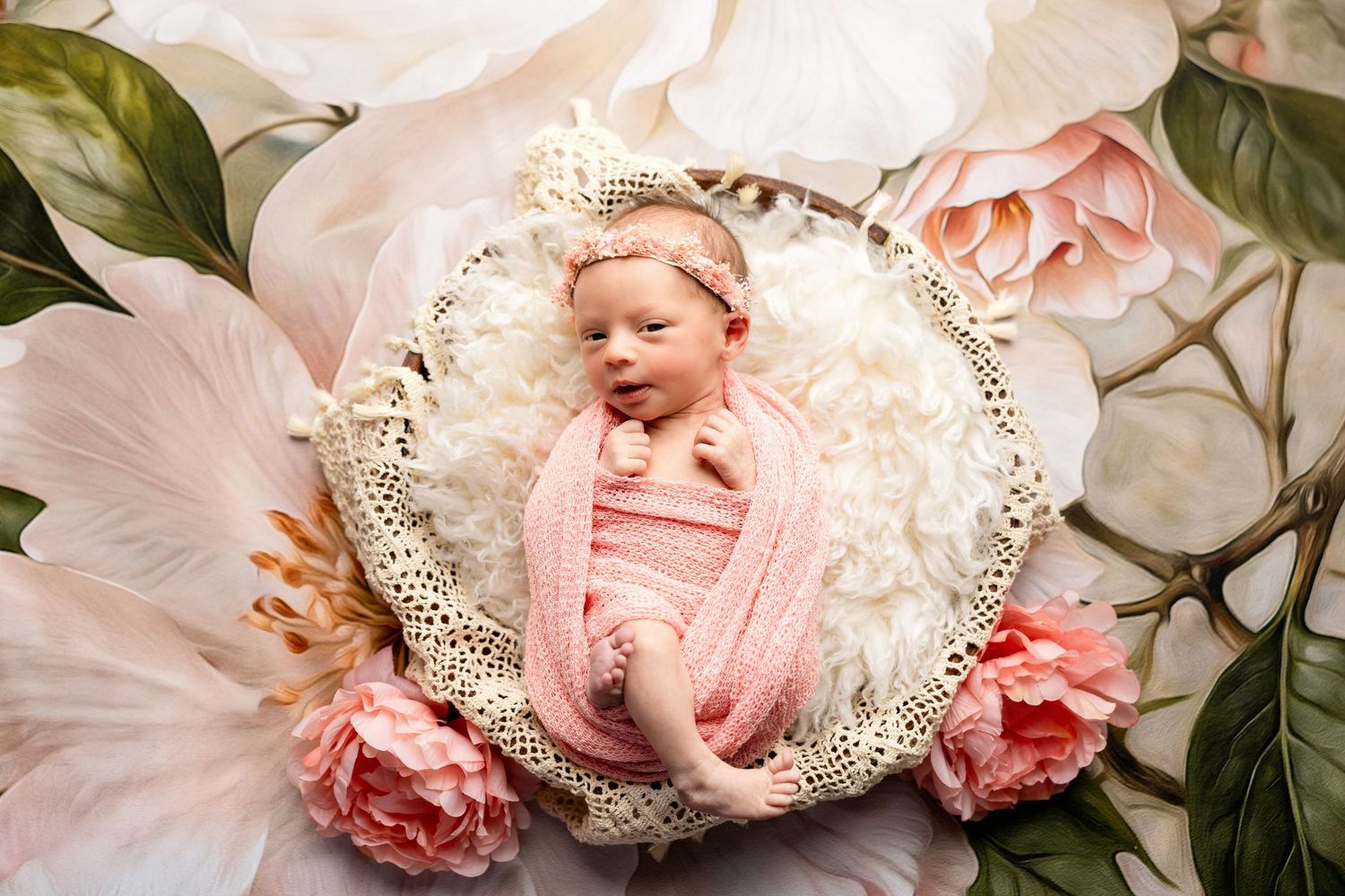 Delicate newborn photography setup with lace and pink roses.