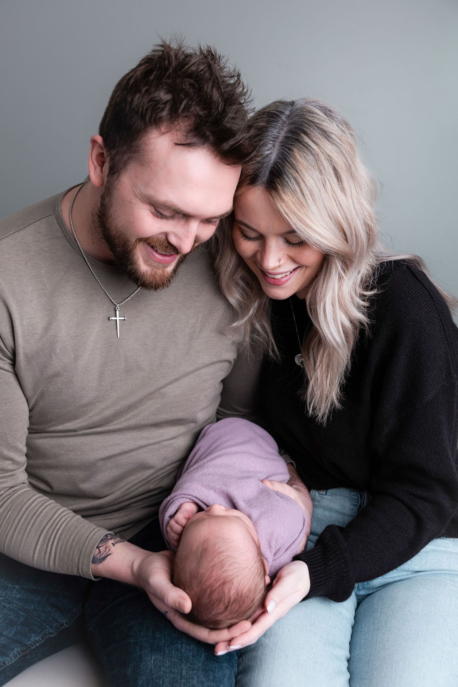 Tender family moment captured during lifestyle photography session on grey couch.