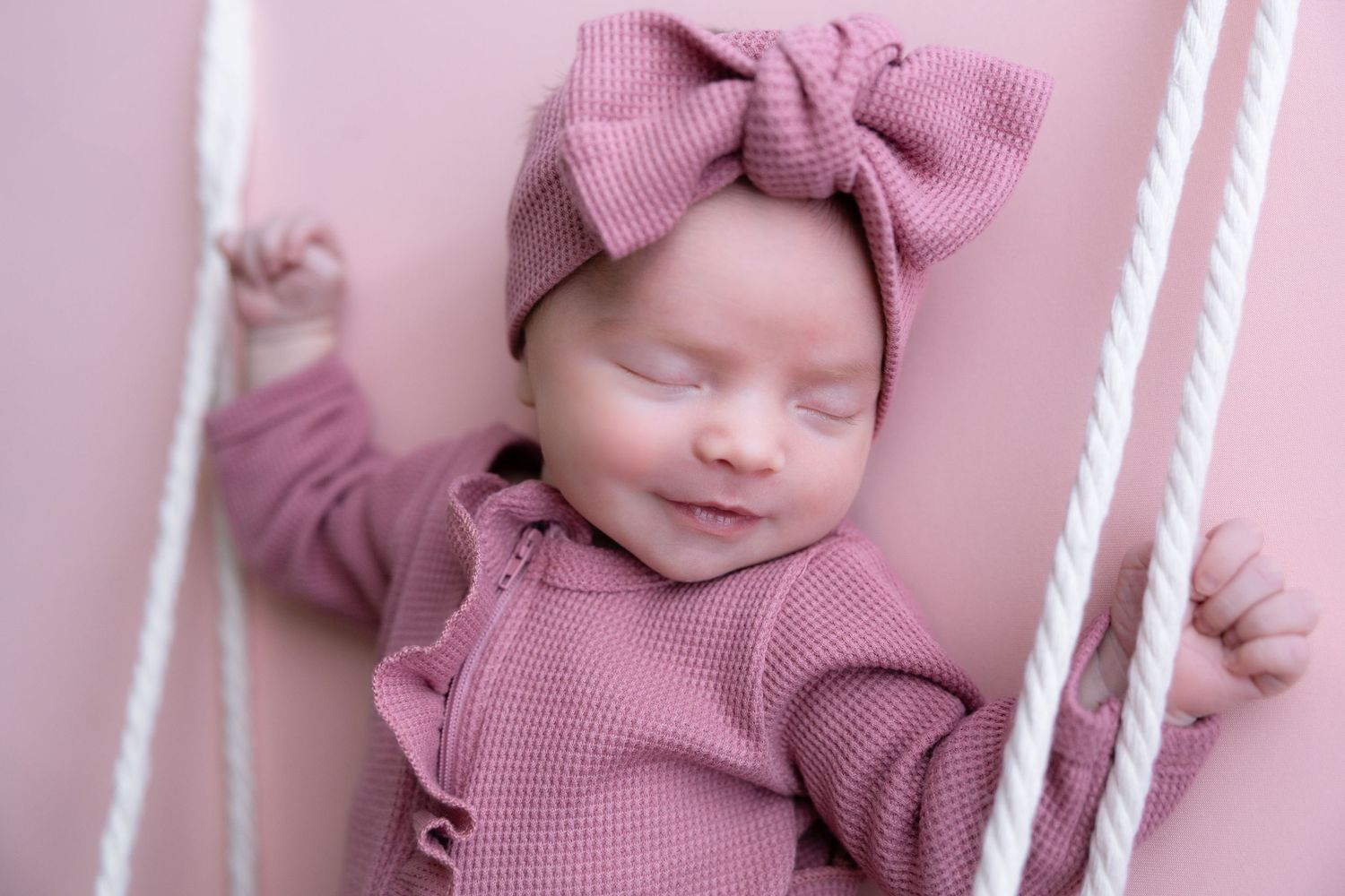 Baby in pink outfit with bow during lifestyle photography session.