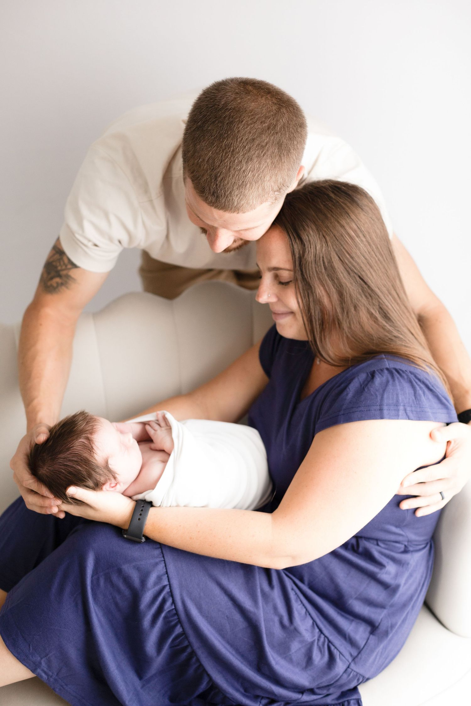 Intimate family moment with parents gazing at their newborn baby while sitting together.