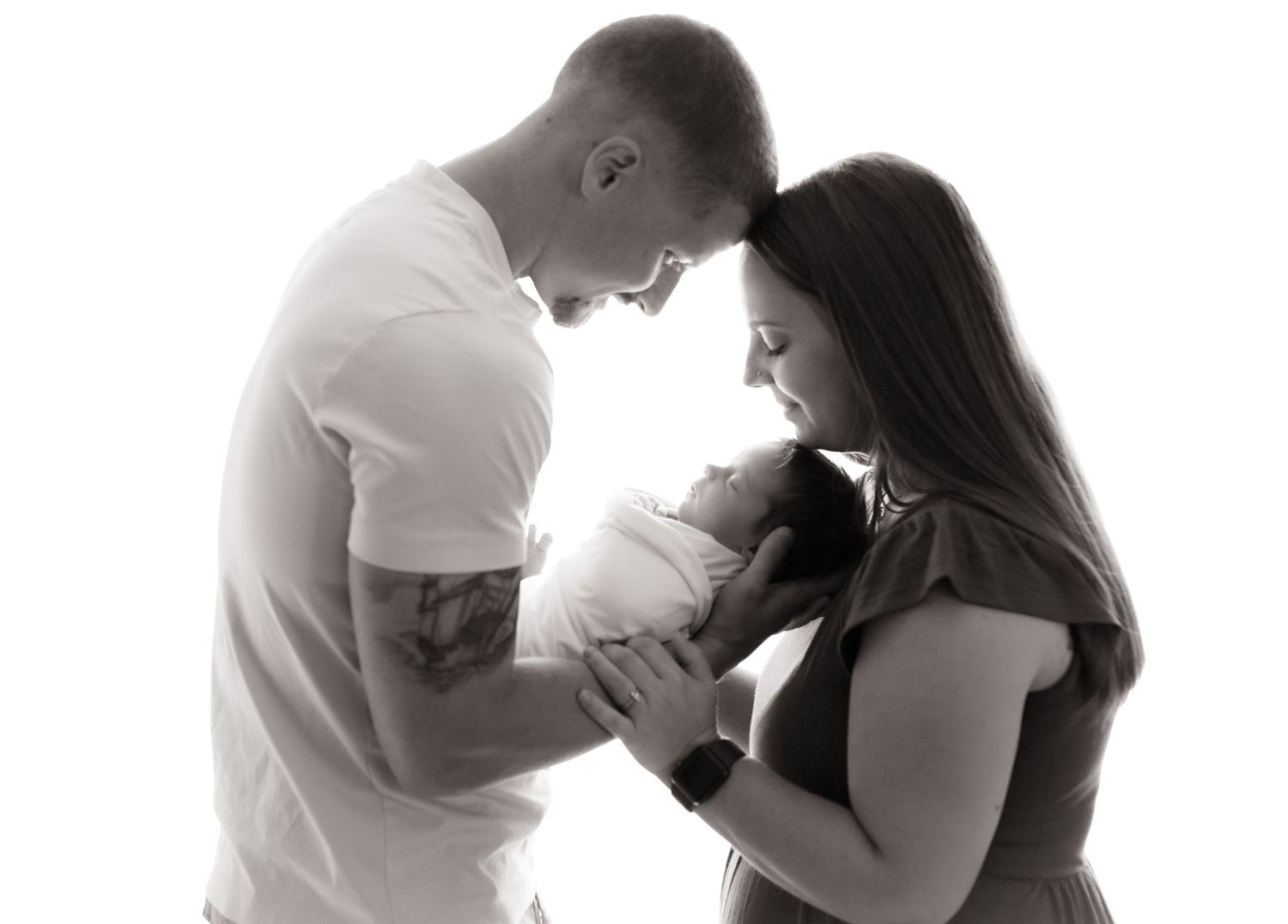 Black and white portrait of parents tenderly cradling their newborn.