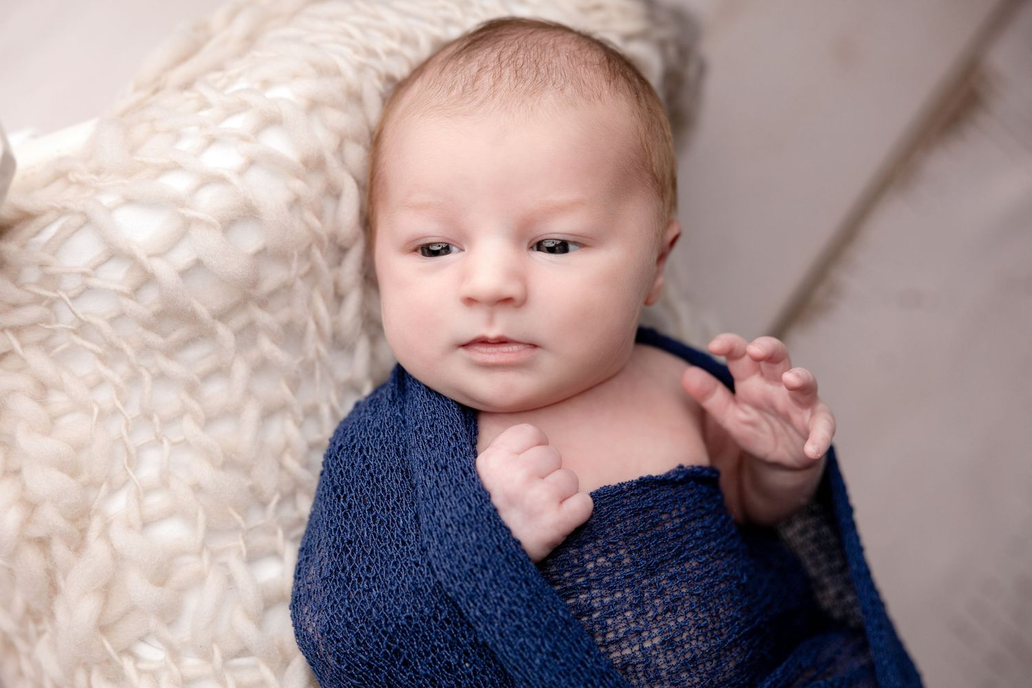Baby wearing navy blue wrap photographed in multiple angles on cream colored backdrop.