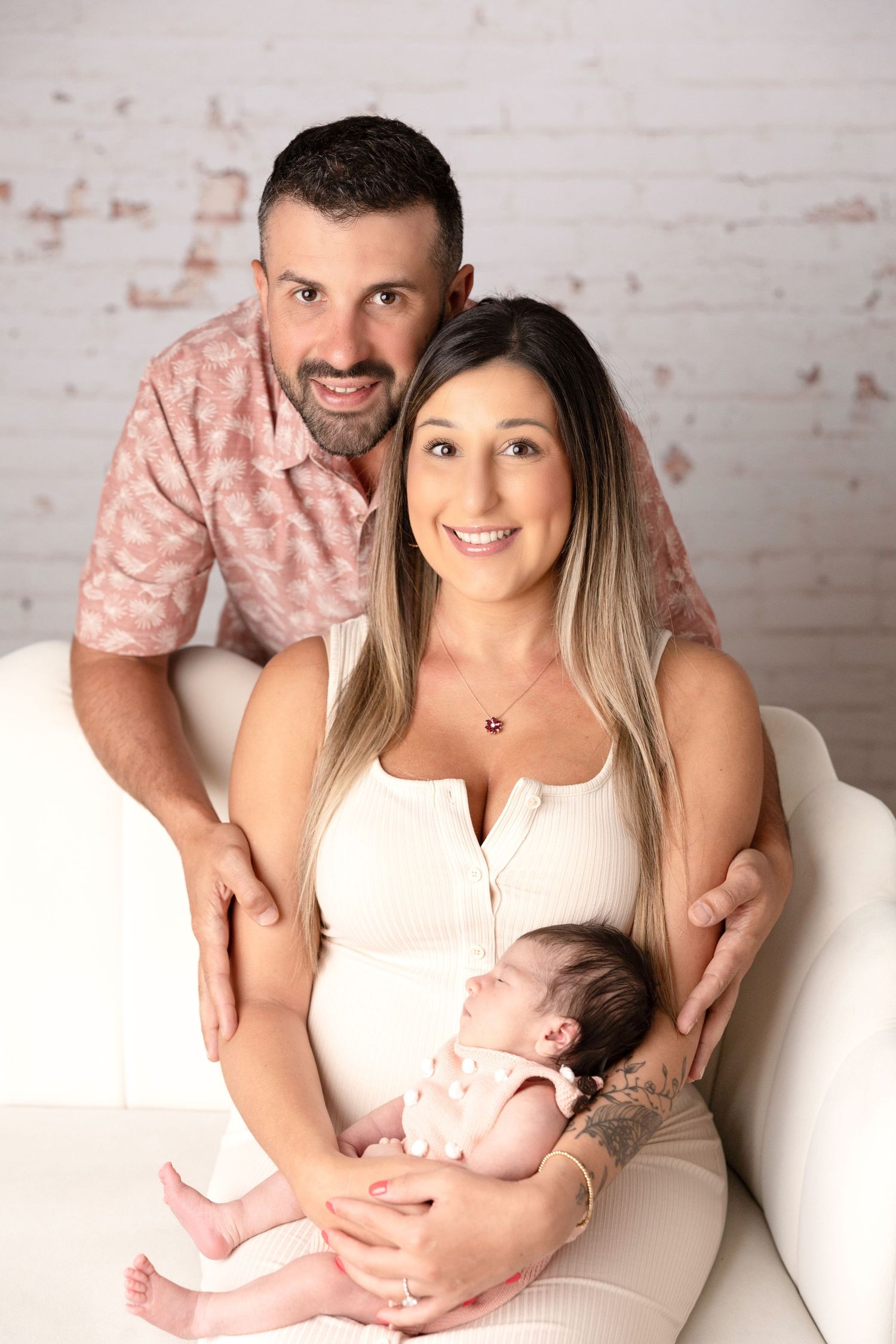 Intimate family portrait session against white brick wall background.