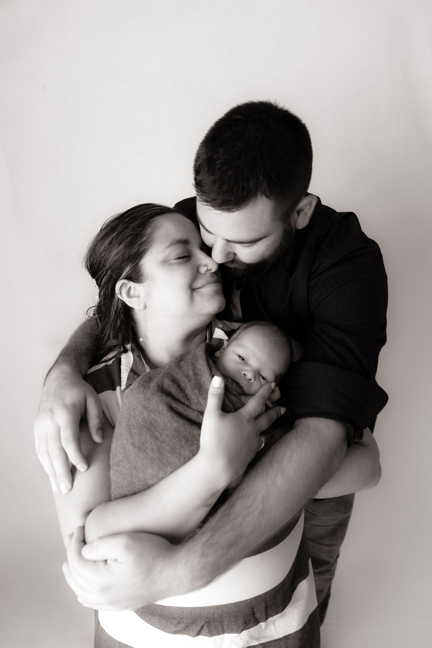Black and white intimate family portrait showing tender moments with baby.