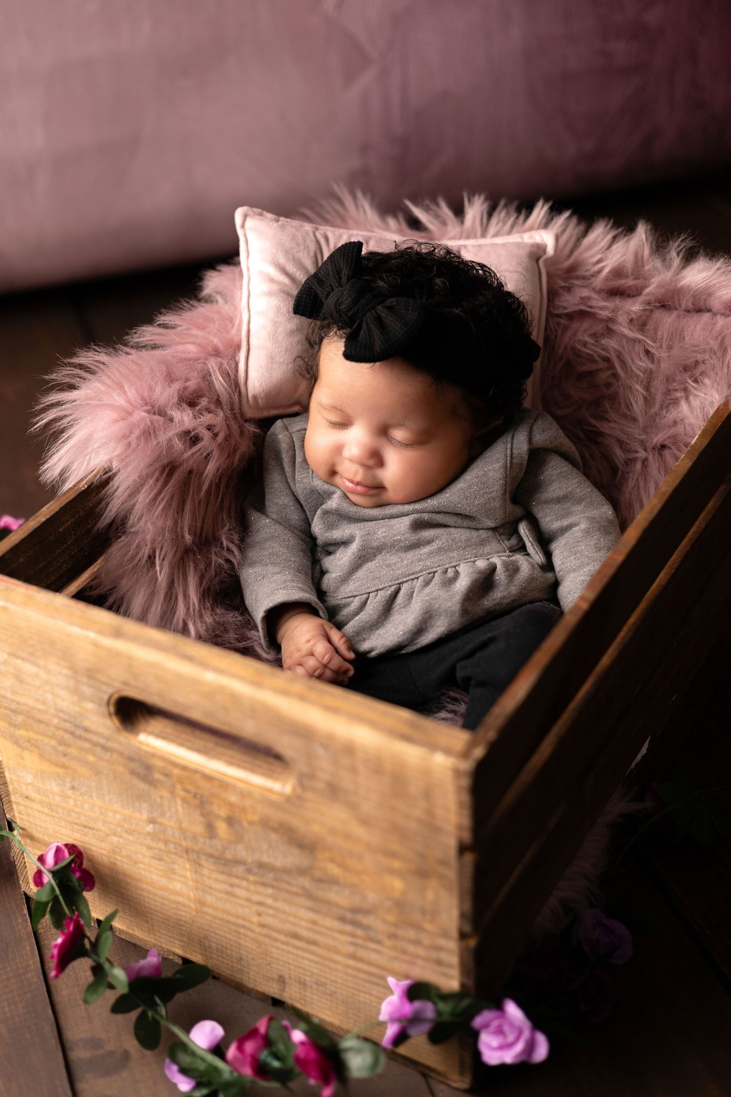 Rustic wooden box with pink fur lining and purple roses in moody lighting.