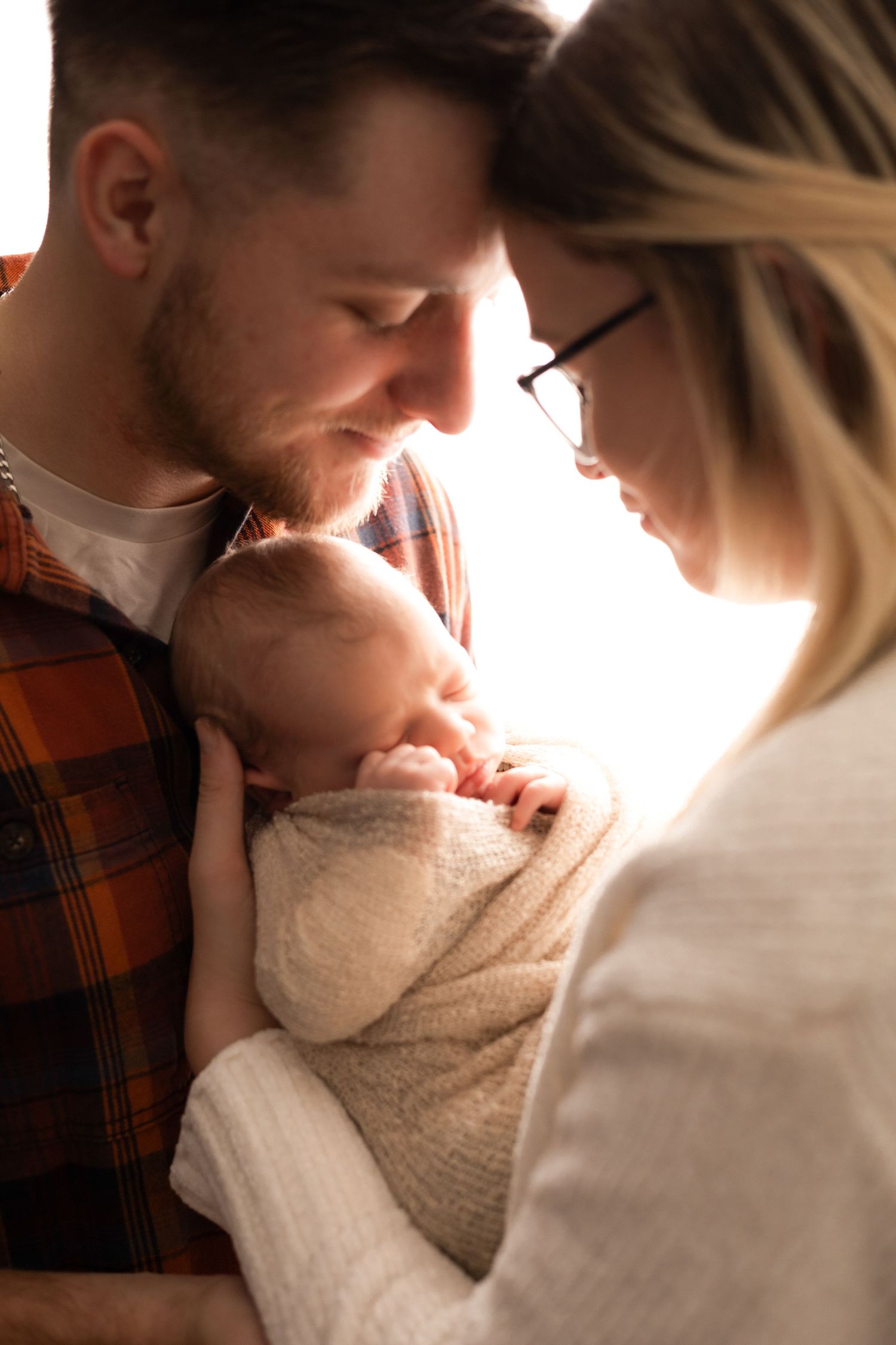 Backlit family portrait series showing intimate moments with newborn baby.